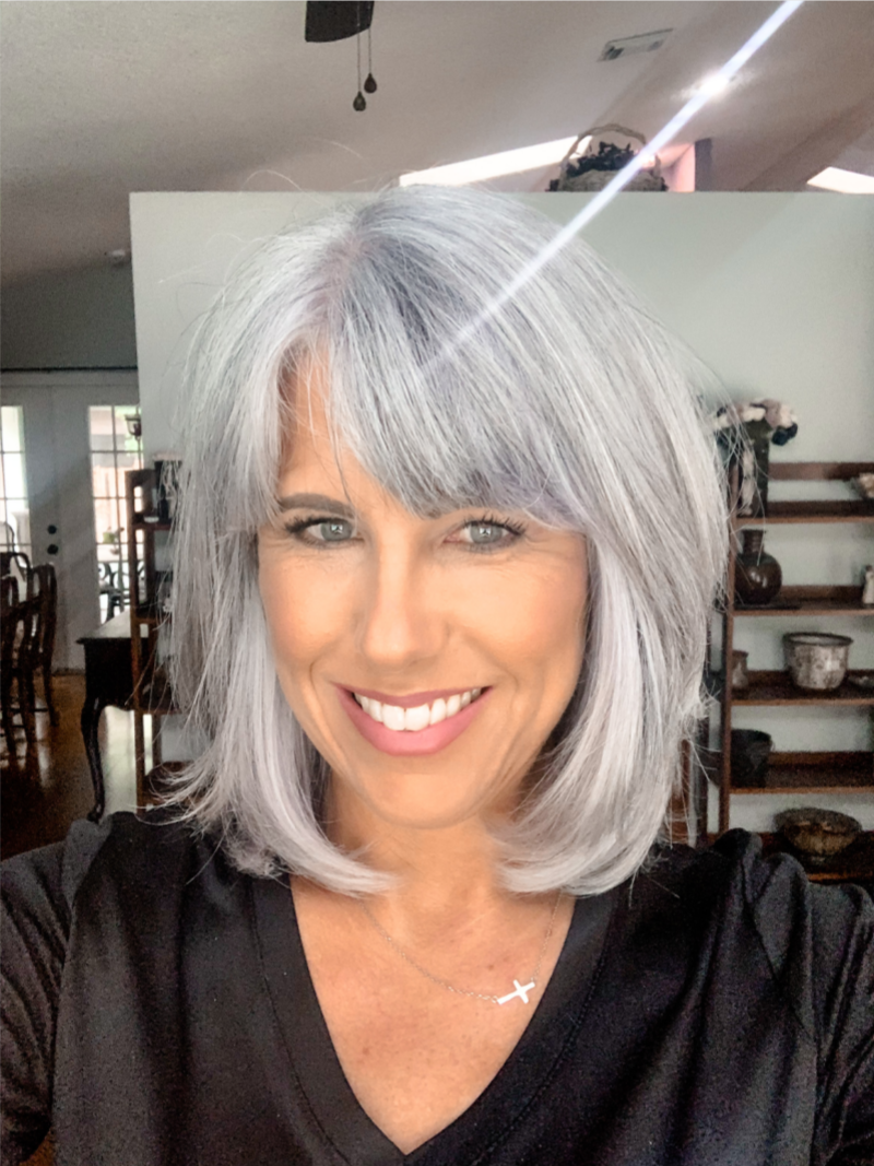 A confident person with full silver/gray hair.